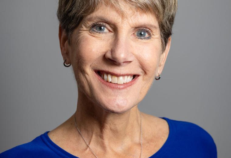 Elaine Appleton Grant headshot. Smiling white woman with short, light brown hair and blue eyes, wearing a dark blue top. Photo credit: Katherine Emery Photography. 